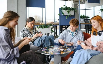 Group of creative friends sitting at wooden table. People having fun while playing board game
